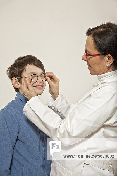 Junge bei Augenärztin  beim Anpassen einer Brille