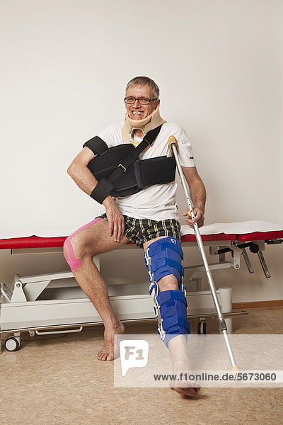 Man with kinesio taping wearing a shoulder abduction pad  a foot orthosis and a cervical support