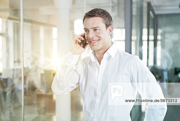 Smiling businessman in office telephoning