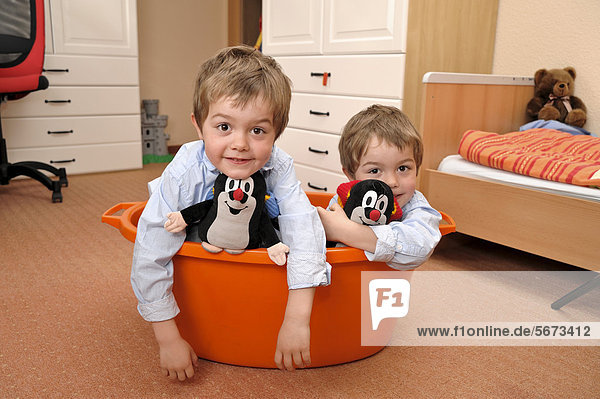 Zwillinge  Jungen  4 Jahre  sitzen in einer orangen Badewanne