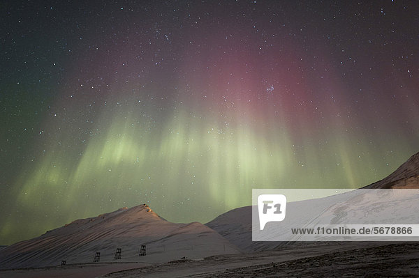 Grüne und rote Polarlichter über schneebedeckter Landschaft und Seilbahn  bei Longyearbyen  Spitzbergen  Svalbard  Norwegen  Europa