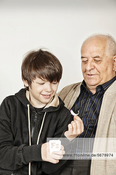Grandson handing over a hearing aid device to his grandfather