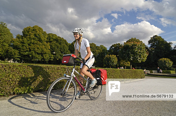 Woman riding her touring bike through the Hofgarten  Court Garden  Munich  Upper Bavaria  Bavaria  Germany  Europe