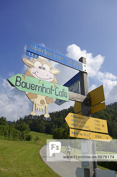 Wegweiser für Bauernhof-Cafe  Paar mit Elektrofahrrädern  Reit im Winkl  Chiemgau  Oberbayern  Bayern  Deutschland  Europa