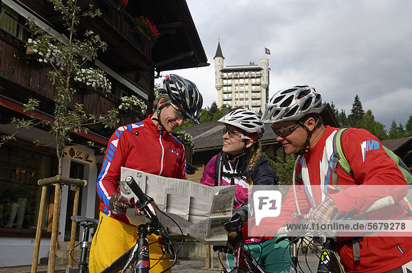 Mountain bikers with a map  outside the Palace Hotel  Gstaad  Municipality of Saanen  Bernese Oberland  Switzerland  Europe