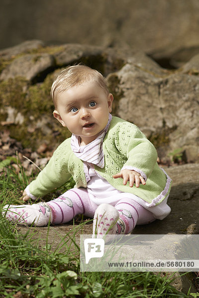 Weibliches Baby sitzt auf einem Stein