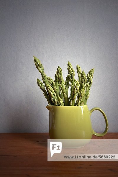 Bunch of green asparagus in a green milk jug