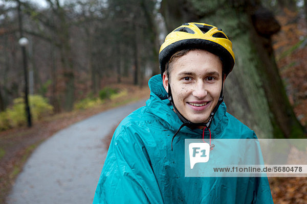 Young man wearing cycling helmet on forest path