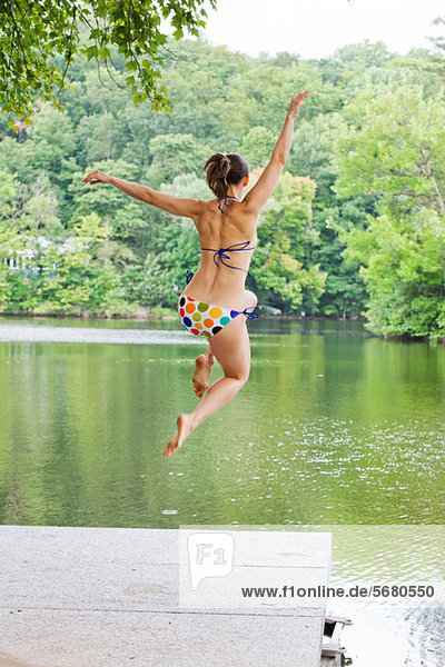 Mid adult woman leaping into river