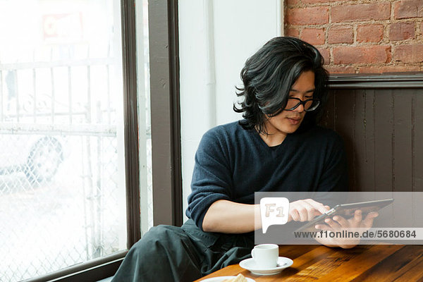 Junger Mann mit digitalem Tablett im Café