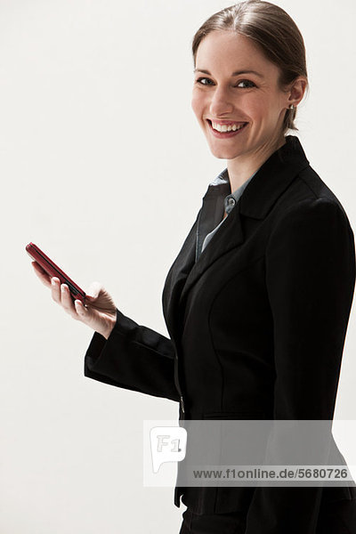 Portrait einer jungen Geschäftsfrau mit Handy  Studioaufnahme