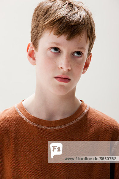Junge in braunem Pullover mit rollenden Augen  Studioaufnahme