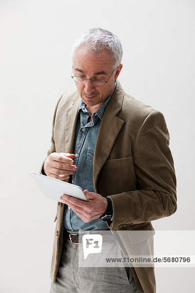 Mature man looking at digital tablet  studio shot