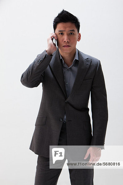 Young Asian businessman using cellphone  studio shot