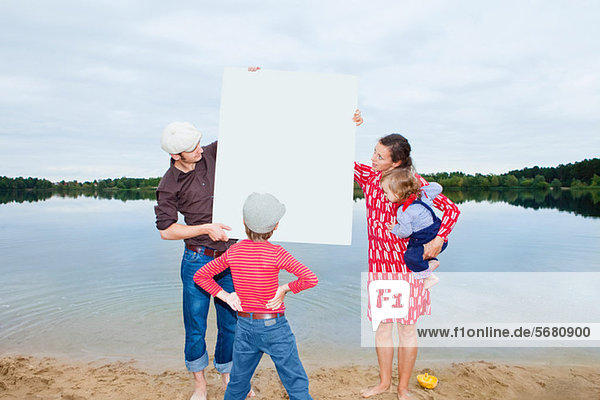 Familie am See  schaut auf ein leeres Schild