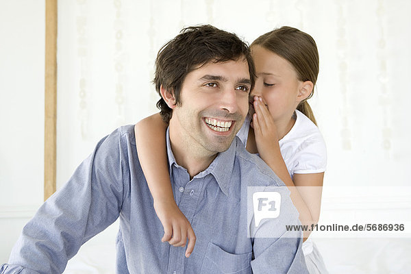 Mädchen flüsternd zu lächelndem Vater