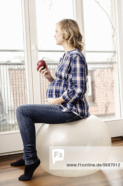 Schwangere Frau auf dem Übungsball sitzend