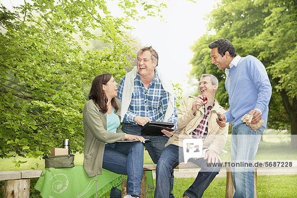 Friends using tablet computer in park