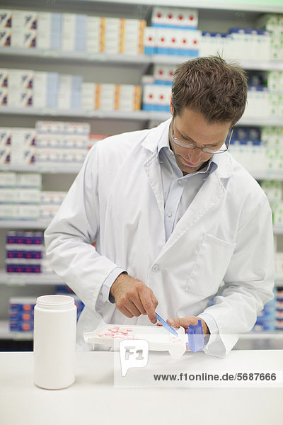 Pharmacist counting pills at counter