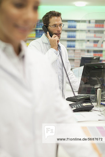 Pharmacist talking on phone at counter