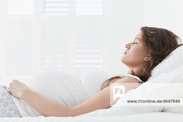 Schwangere Frau schläft auf dem Bett