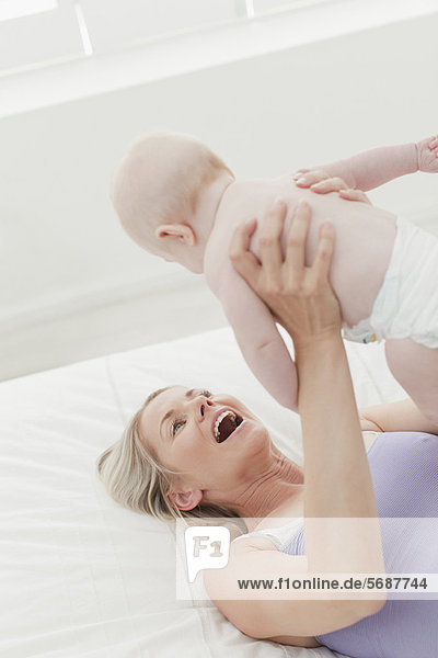 Mother playing with baby on bed