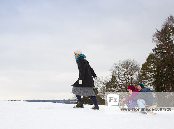 Mutter zieht Kinder auf Schlitten im Schnee