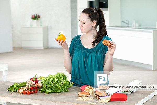 Woman with fast food and vegetables