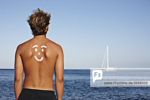 Junge mit Zeichnung in Sonnencreme auf dem Rücken