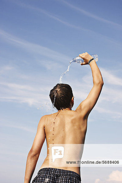 Teenage boy pouring water on himself