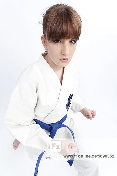 Junge Frau im Karate-Gewand mit blauem Gürtel in Kampfstellung