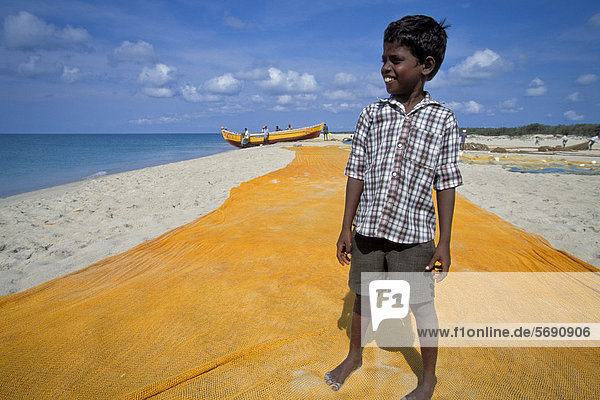 Junge  Sohn eines Fischers  gelbes Fischernetz  Fischerboot  Adam's Bridge  bei Rameshwaram oder Ramesvaram  Tamil Nadu  Südindien  Indien  Asien