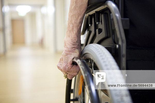Elderly woman  detailed view of the hand moving a wheelchair  at a nursing home