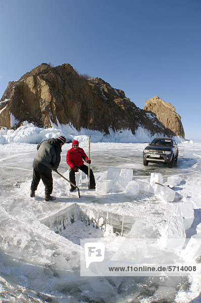 Männer sägen ein Loch ins Eis  Vorbereitungen fürs Eistauchen  Baikalsee  Insel Olchon  Sibirien  Russland  Eurasien