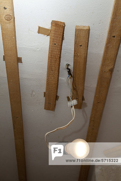 Glühlampe mit Lüsterklemmen und Holzleisten unter der Decke eines Wohnraums