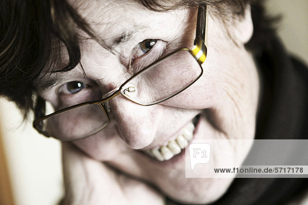 Lächelnde Seniorin schaut über Brillenrand