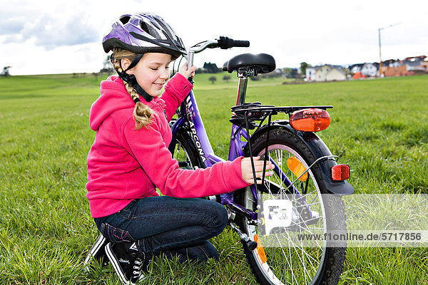 Girl wearing a cycling helmet  checking her bicycle