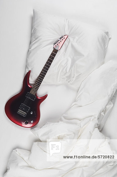 Rote Gitarre auf dem Bett