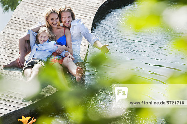 Österreich  Salzburger Land  Familie sitzend auf Brücke über Naturbad