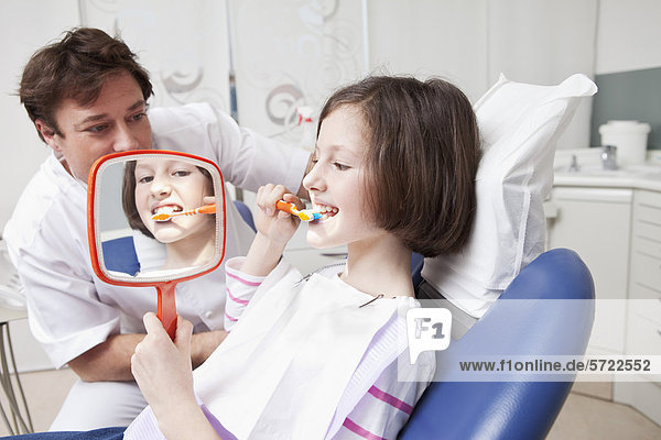 Germany  Bavaria  Patient brushing teeth while doctor looking at her