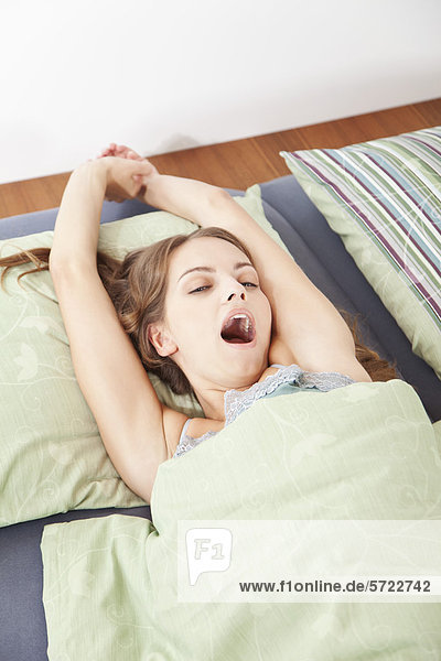 Young woman waking up  stretching on bed