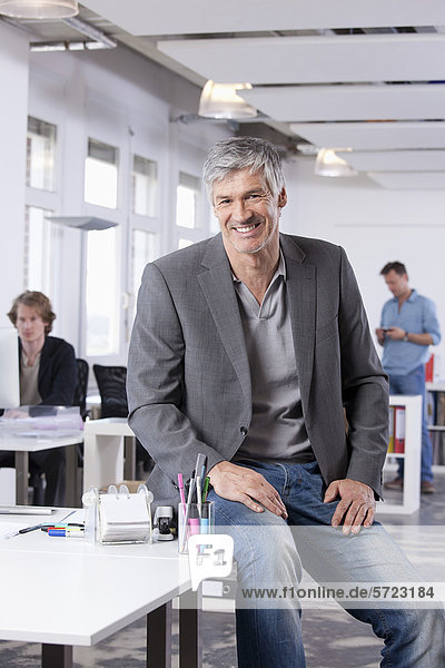 Mature man smiling  colleagues in background