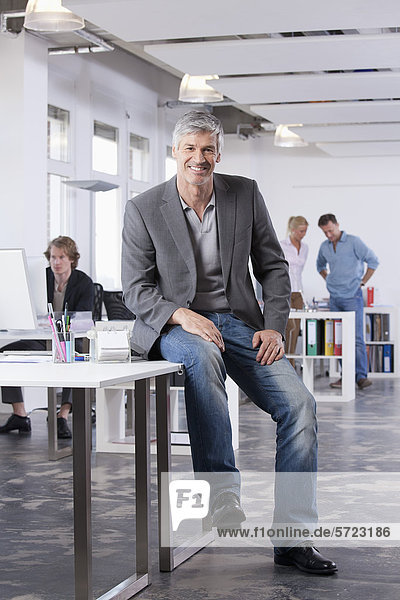 Mature man smiling  colleagues in background
