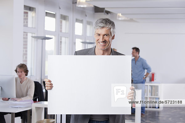 Mature man holding placard in office