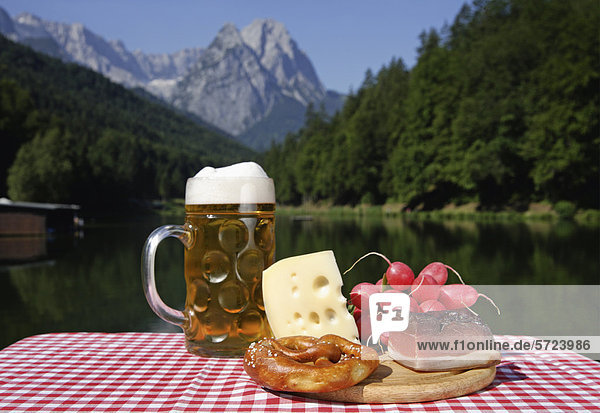 Deutschland  Oberbayern  Bayerische Snacks auf dem Tisch  Berg mit See im Hintergrund