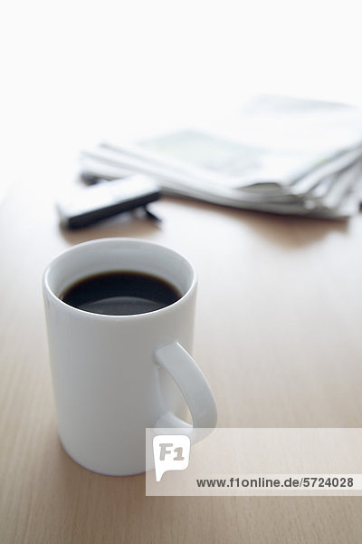 Tasse Kaffee  Zeitung  Handy und Stift auf Bürotisch  Nahaufnahme