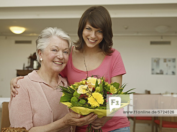 Frauen mit Blumenstrauß im Pflegeheim  lächelnd  Portrait