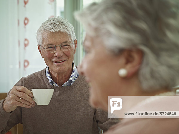 Senior Mann mit Tasse  Frau lächelnd im Vordergrund