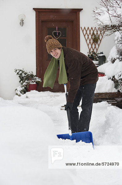 Austria  Young man shoveling snow in front of house  portrait