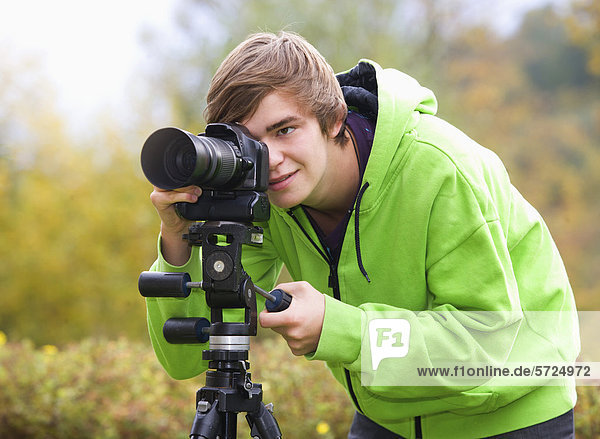 Österreich  Junger Mann beim Fotografieren  lächelnd